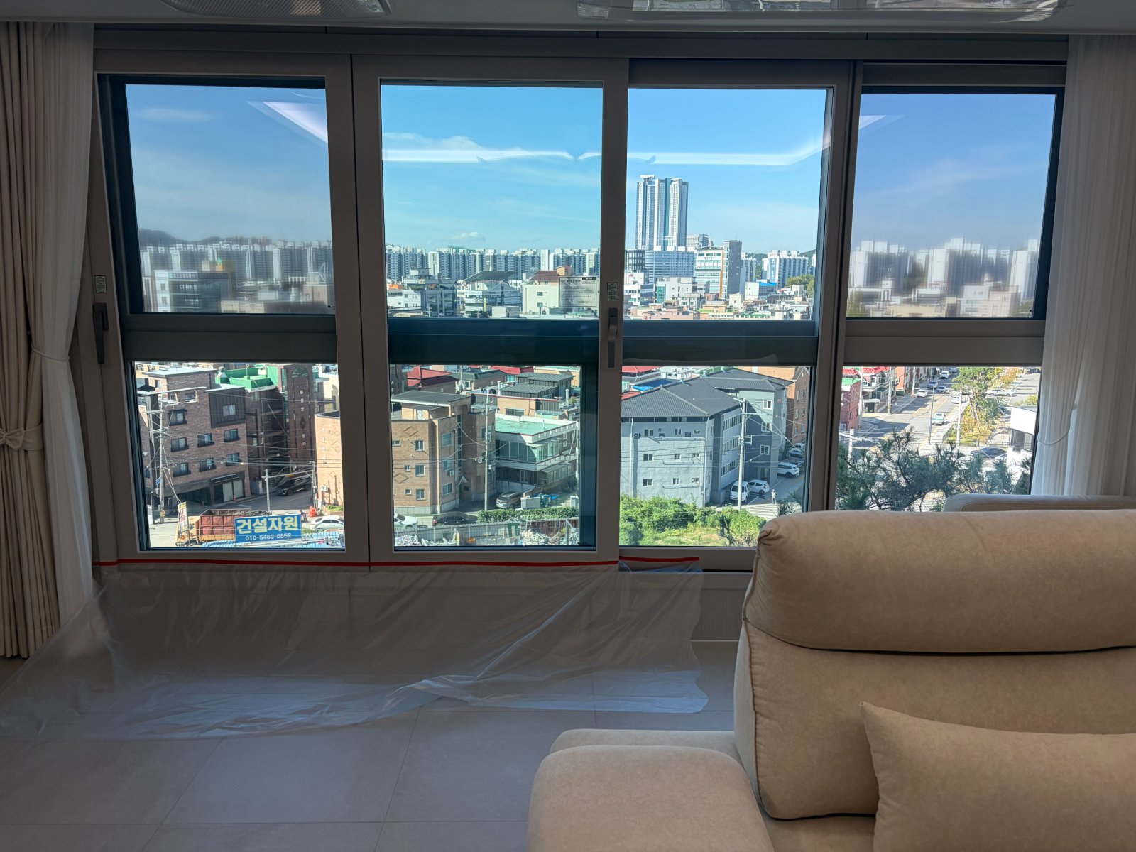 거실 창, 필름 작업 전 바닥에 보호비닐을 깔고 창 하단에 빨간 테이프로 경계를 표시한 모습